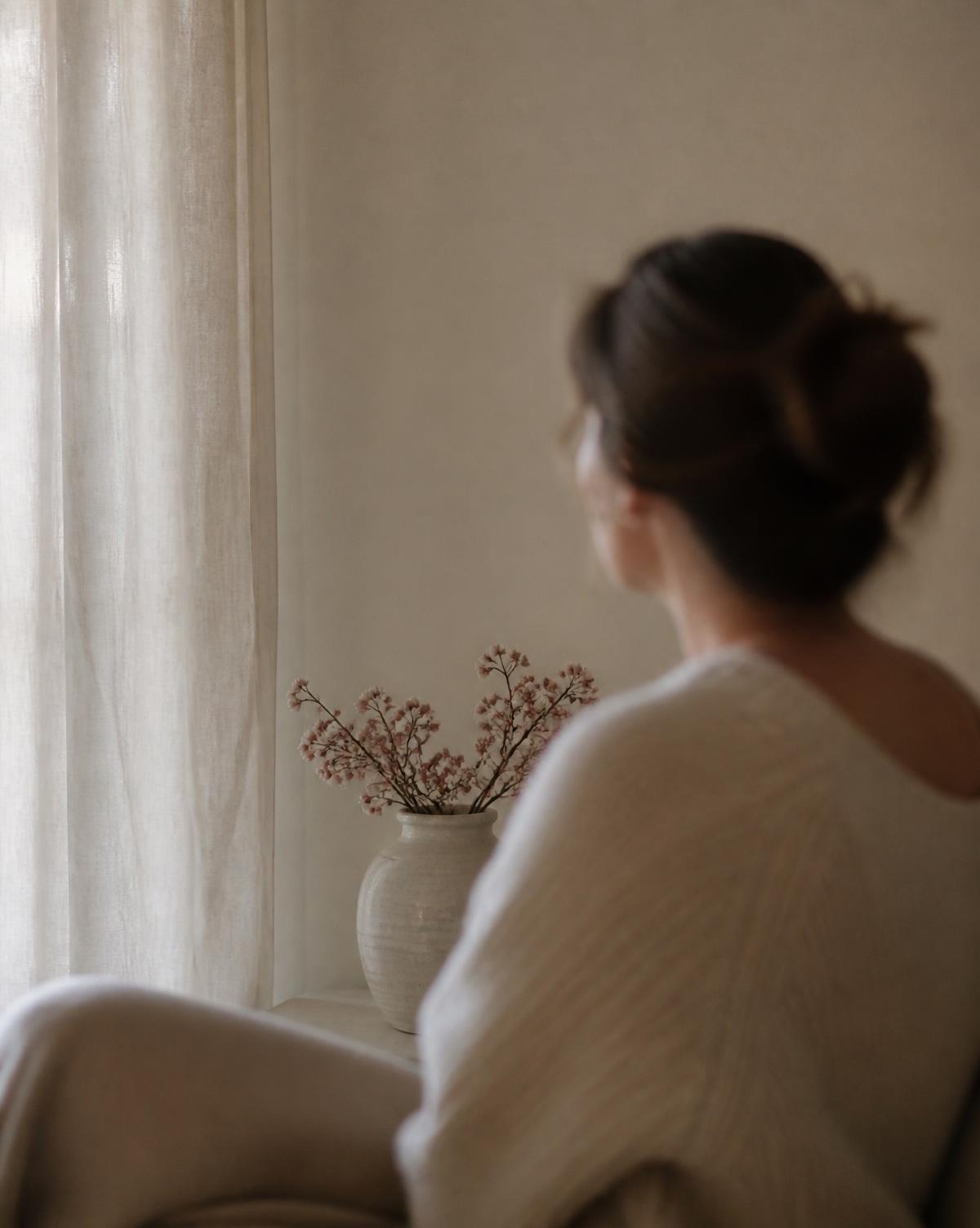 Mujer serena junto a una ventana con luz suave
